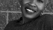 Portrait of a woman with an expressive smile and a joyful demeanor. The background is out of focus, emphasizing the subject. Her attire suggests a formal or semi-formal occasion, perhaps indicating an event or gathering. The lighting highlights her facial features, contributing to the overall positive vibe of the image. The photographer has skillfully used depth of field to draw attention to the subject, while also providing a sense of the setting. A strong image for anyone looking for uplifting content that conveys a sense of positivity and confidence.